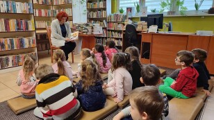 dzieci słuchające czytanej przez bibliotekarkę książki