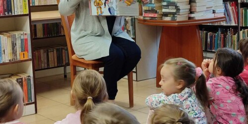 przedszkolaki słuchające czytanej przez bibliotekarkę książki