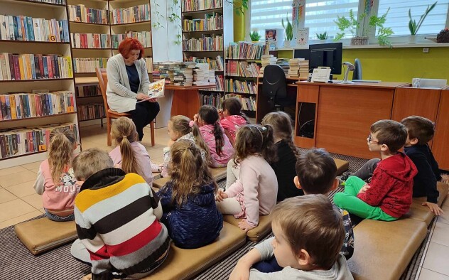 dzieci słuchające czytanej przez bibliotekarkę książki