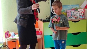 Prowadząca audycję kobieta i chłopiec z bukietem kwiatów